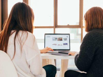 two women looking at the laptop working together