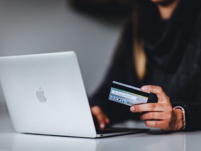 hands holding credit card while on laptop