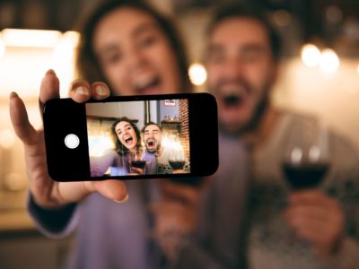 man and woman taking a selfie together holding wine glass