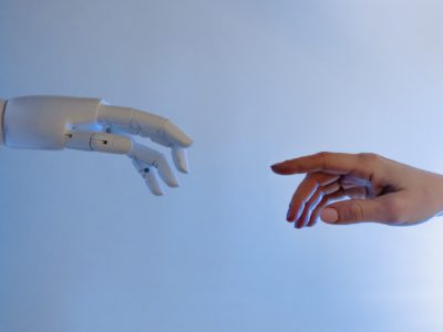 human hands and robot's hand reaching for each other
