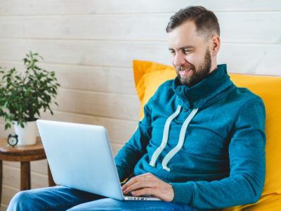 man smiling while working on laptop