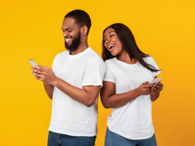 portrait of smiling young couple looking at their phones