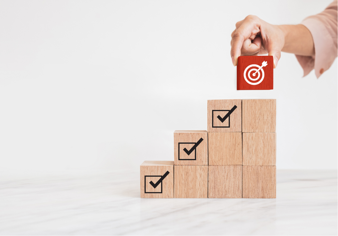 Hand placing a target block on wooden steps with checkmarks, showing how a HubSpot agency Philippines achieves goals using clean CRM data.
