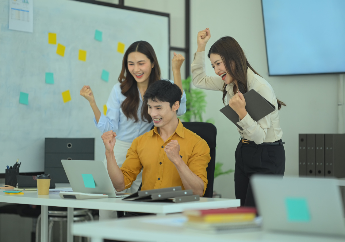 Excited sales team celebrating business results on a laptop, representing revenue growth after transitioning from spreadsheets to a CRM like HubSpot