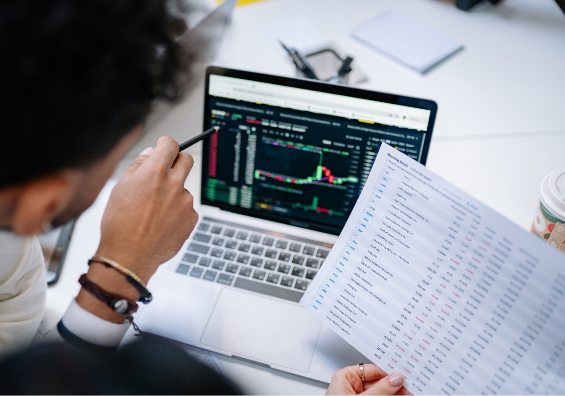 Person reviewing printed spreadsheet data alongside a laptop, illustrating the limitations of manual spreadsheet tracking for growing sales teams