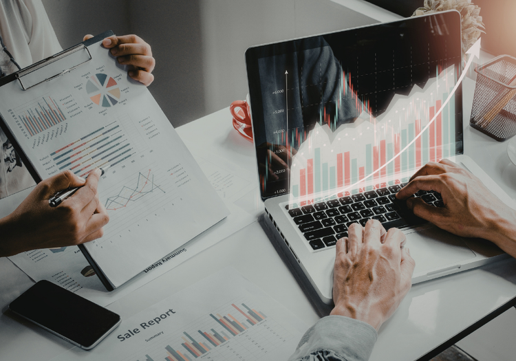 Two professionals analyzing sales growth charts and reports on a laptop, representing a data-driven system for sales.